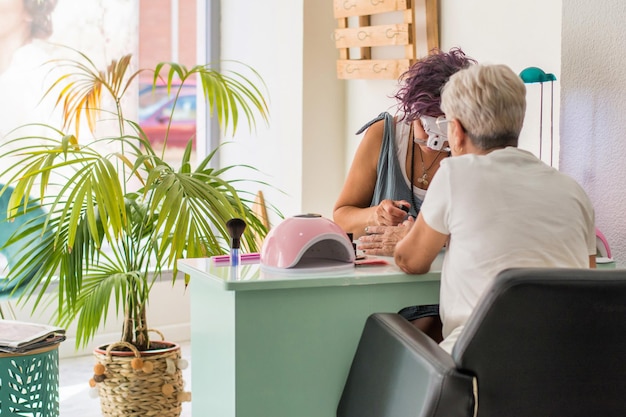 older woman getting manicure beauty salon beautician working her workspace small business 180241 7